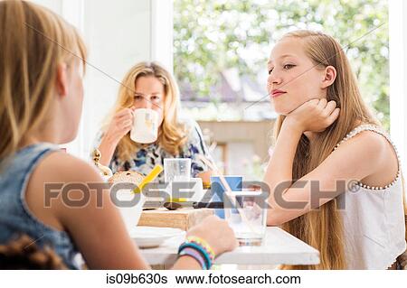 Portrait of mother and daughters in kitchen having breakfast together View Large Photo Image Stock Photograph - Portrait of mother and daughters in kitchen having breakfast together. Fotosearch