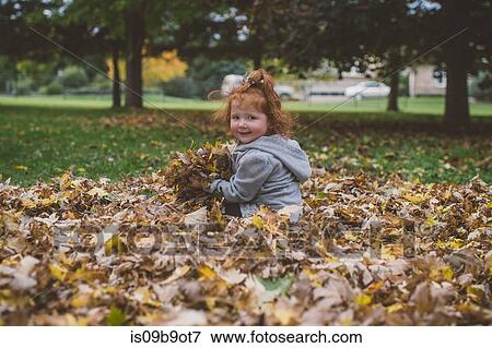 Portrait of red haired female toddler in park with bundles of autumn leaves View Large Photo Image Stock Photo - Portrait of red haired female toddler in park with bundles of autumn leaves. Fotosearch