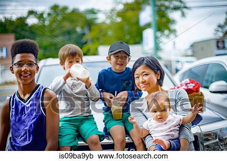 Stock Image - Portrait of teenage boy with woman and her children on street. Fotosearch