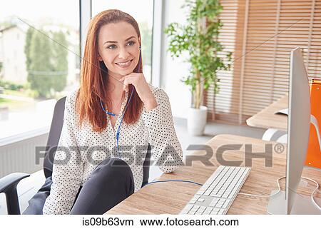 Portrait of woman at desk looking away smiling View Large Photo Image Picture - Portrait of woman at desk looking away smiling. Fotosearch