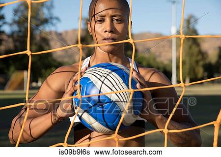 Portrait of woman behind football goat net holding football looking at camera View Large Photo Image Stock Photograph - Portrait of woman behind football goat net holding football looking at camera. Fotosearch