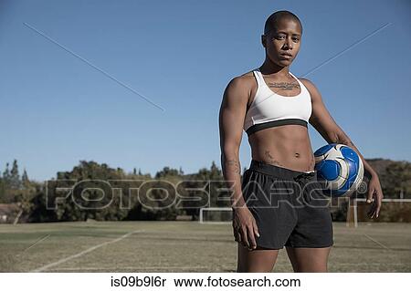 Stock Photography - Portrait of woman holding football looking at camera. Fotosearch