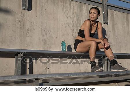 Portrait of woman in sport clothing sitting on bench looking away View Large Photo Image Stock Photo - Portrait of woman in sport clothing sitting on bench looking away. Fotosearch