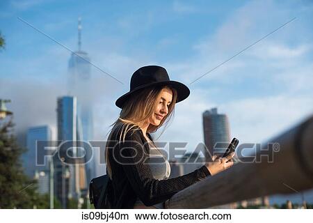 Picture - Portrait of woman looking at mobile phone smiling, New York, USA. Fotosearch