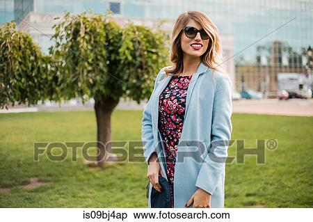 Stock Photography - Portrait of woman wearing sunglasses looking at camera smiling. Fotosearch