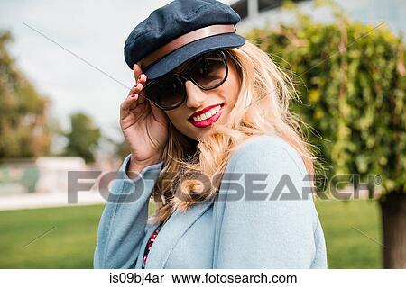 Portrait of woman wearing sunglasses and baker boy cap looking at camera smiling View Large Photo Image Stock Photography - Portrait of woman wearing sunglasses and baker boy cap looking at camera smiling. Fotosearch