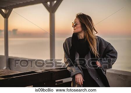 Picture - Portrait of woman wearing winter coat and sunglasses looking away, Odessa, Odeska Oblast, Ukraine. Fotosearch