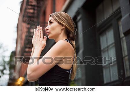 Stock Photo - Portrait of woman with hands together looking away, New York, USA. Fotosearch