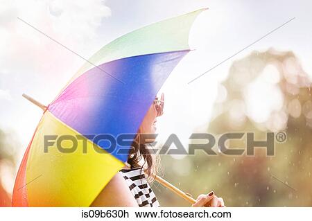 Stock Image - Portrait of woman with umbrella looking away. Fotosearch