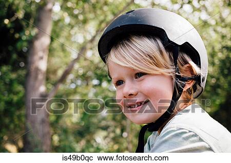 Stock Image - Portrait of young boy, outdoors, wearing safety helmet. Fotosearch
