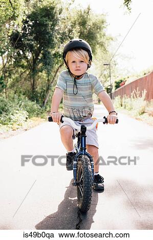Stock Image - Portrait of young boy riding bicycle outdoors. Fotosearch