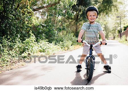 Stock Image - Portrait of young boy riding bicycle outdoors. Fotosearch