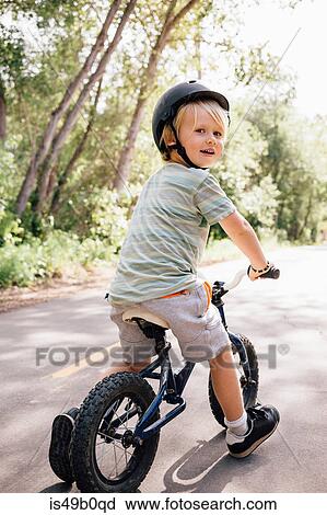 Stock Image - Portrait of young boy riding bicycle outdoors. Fotosearch