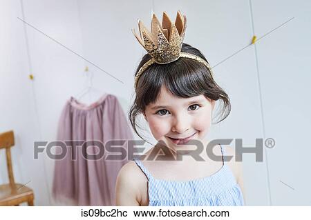 Stock Image - Portrait of young girl wearing crown headband, smiling. Fotosearch