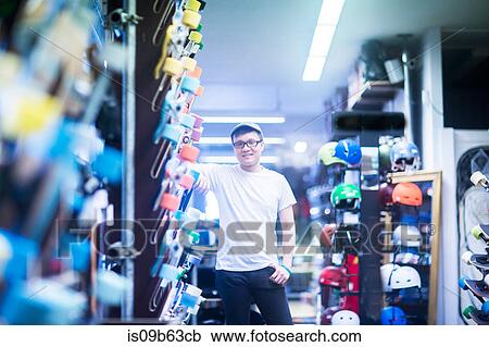 Stock Image - Portrait of young male sales assistant in skateboard shop. Fotosearch