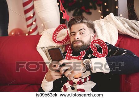 Portrait of young man wrapped in christmas decorations at christmas party View Large Photo Image Stock Image - Portrait of young man wrapped in christmas decorations at christmas party. Fotosearch