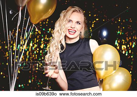 Portrait of young woman at party, holding champagne glass View Large Photo Image Picture - Portrait of young woman at party, holding champagne glass. Fotosearch