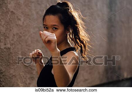 Portrait of young woman exercising outdoors, in fighting stance View Large Photo Image Stock Image - Portrait of young woman exercising outdoors, in fighting stance. Fotosearch