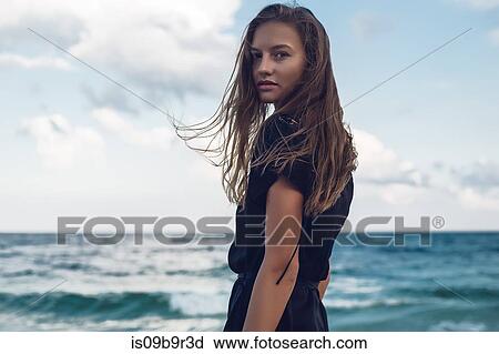 Stock Image - Portrait of young woman looking over her shoulder on beach, Odessa, Odessa Oblast, Ukraine. Fotosearch