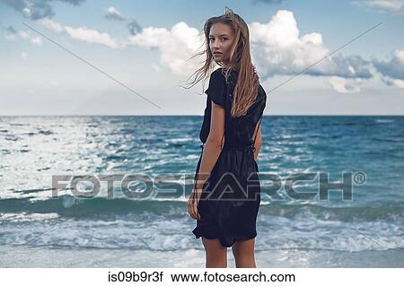 Stock Image - Portrait of young woman looking over her shoulder on beach, Odessa, Odessa Oblast, Ukraine. Fotosearch