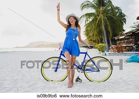 Stock Photograph - Portrait of young woman with bicycle on sandy beach, Krabi, Thailand. Fotosearch
