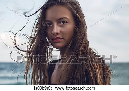 Stock Image - Portrait of young woman with flyaway long hair on beach, Odessa, Odessa Oblast, Ukraine. Fotosearch