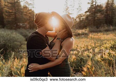 Stock Image - Pregnant mid adult couple about to kiss in rural valley at sunset, Mineral King, California, USA. Fotosearch