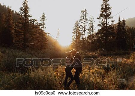 Stock Image - Pregnant mid adult couple face to face in rural valley at sunset, Mineral King, California, USA. Fotosearch