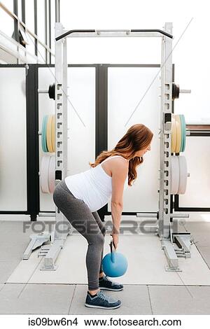 Picture - Pregnant woman exercising with kettle bell on balcony. Fotosearch