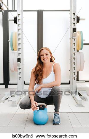 Stock Photography - Pregnant woman exercising with kettle bell on balcony. Fotosearch