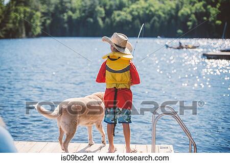 Rear view of dog and boy in cowboy hat fishing from lake pier View Large Photo Image Stock Photograph - Rear view of dog and boy in cowboy hat fishing from lake pier. Fotosearch