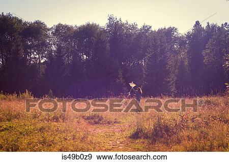 Stock Photo - Rear view of teenage girl running with kite in field. Fotosearch