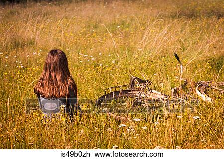 Rear view of teenage girl with bicycle sitting in long grassy field View Large Photo Image Stock Image - Rear view of teenage girl with bicycle sitting in long grassy field. Fotosearch