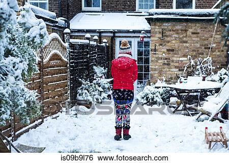 Rear view of woman standing in snow covered garden View Large Photo Image Stock Photograph - Rear view of woman standing in snow covered garden. Fotosearch