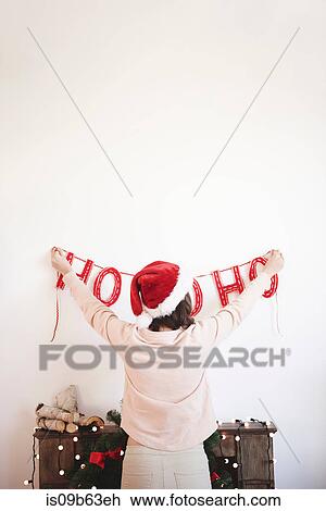Rear view of young woman putting up christmas decorations on wall View Large Photo Image Stock Image - Rear view of young woman putting up christmas decorations on wall. Fotosearch