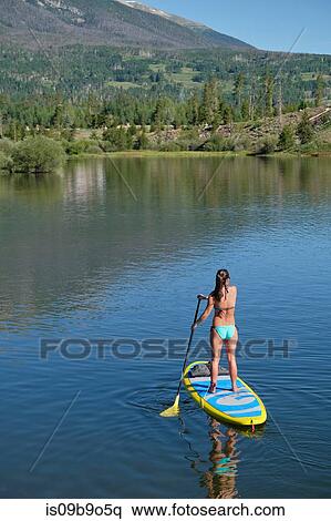 Rear view of young woman stand up paddleboarding on lake, Frisco, Colorado, USA View Large Photo Image Stock Photography - Rear view of young woman stand up paddleboarding on lake, Frisco, Colorado, USA. Fotosearch