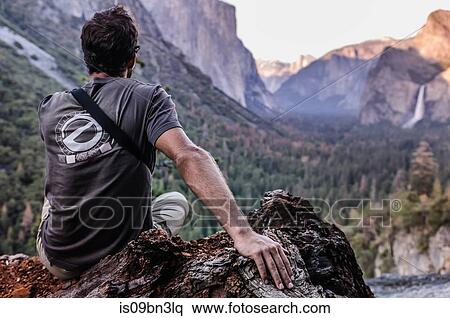 Stock Photography - Rock climber looking out at mountain ranges, Yosemite National Park, California, USA. Fotosearch