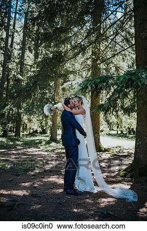Stock Image - Romantic groom lifting up bride to kiss in woodland. Fotosearch