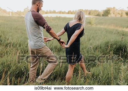 Romantic man and girlfriend strolling in field of sunlit long grass View Large Photo Image Stock Image - Romantic man and girlfriend strolling in field of sunlit long grass. Fotosearch