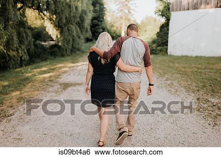 Romantic man and girlfriend strolling hand in hand on rural dirt track, rear view View Large Photo Image Stock Photograph - Romantic man and girlfriend strolling hand in hand on rural dirt track, rear view. Fotosearch