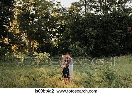Stock Image - Romantic man hugging girlfriend in field of long grass. Fotosearch