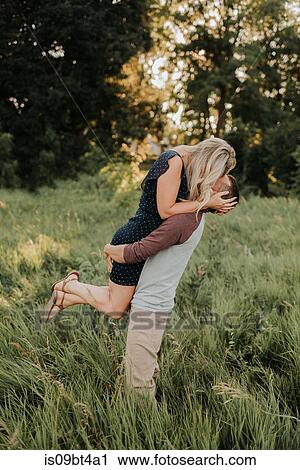 Romantic man lifting up girlfriend in field of long grass View Large Photo Image Stock Image - Romantic man lifting up girlfriend in field of long grass. Fotosearch