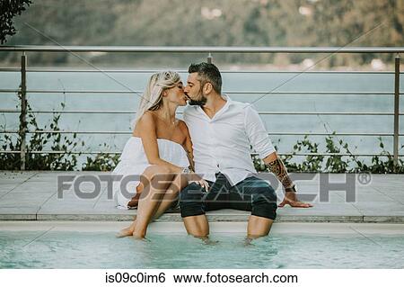 Stock Photograph - Romantic mid adult couple kissing on poolside, Stresa, Piemonte, Italy. Fotosearch