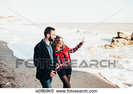 Stock Image - Romantic mid adult couple pointing from beach, Odessa Oblast, Ukraine. Fotosearch