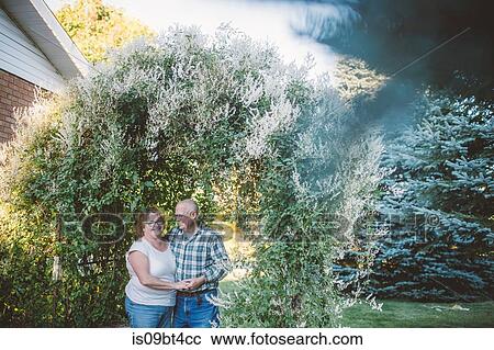 Stock Image - Romantic senior man holding hands with wife in garden. Fotosearch