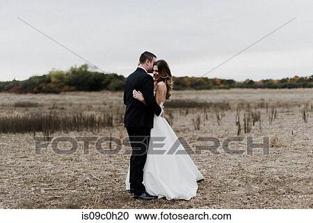 Romantic young bride and groom hugging in field, full length View Large Photo Image Stock Image - Romantic young bride and groom hugging in field, full length. Fotosearch