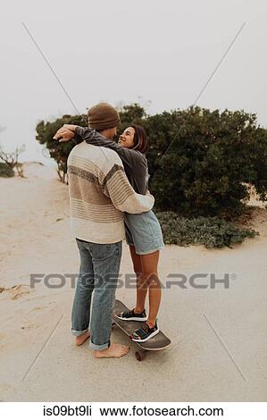 Stock Image - Romantic young skateboarding couple face to face on beach, Jalama, California, USA. Fotosearch
