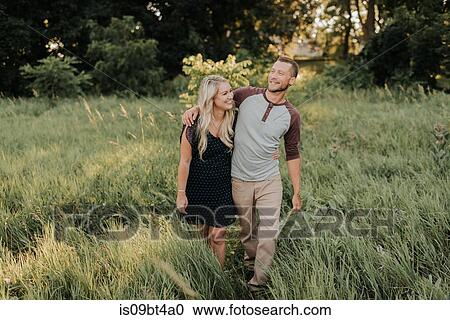 Romantic young woman and boyfriend strolling in field of long grass View Large Photo Image Stock Image - Romantic young woman and boyfriend strolling in field of long grass. Fotosearch