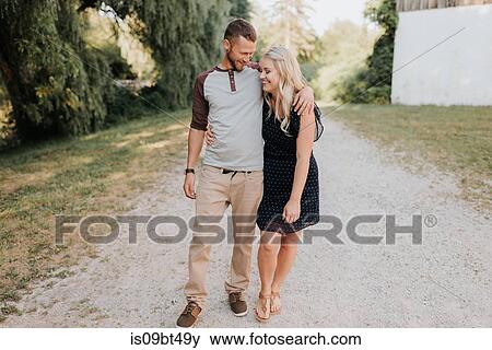 Romantic young woman and boyfriend strolling along dirt track View Large Photo Image Stock Photo - Romantic young woman and boyfriend strolling along dirt track. Fotosearch