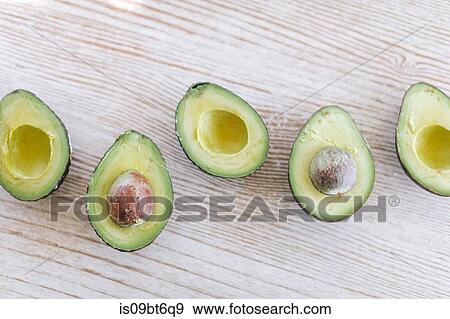 Row of halved avocado on wooden table, overhead still life View Large Photo Image Stock Photo - Row of halved avocado on wooden table, overhead still life. Fotosearch